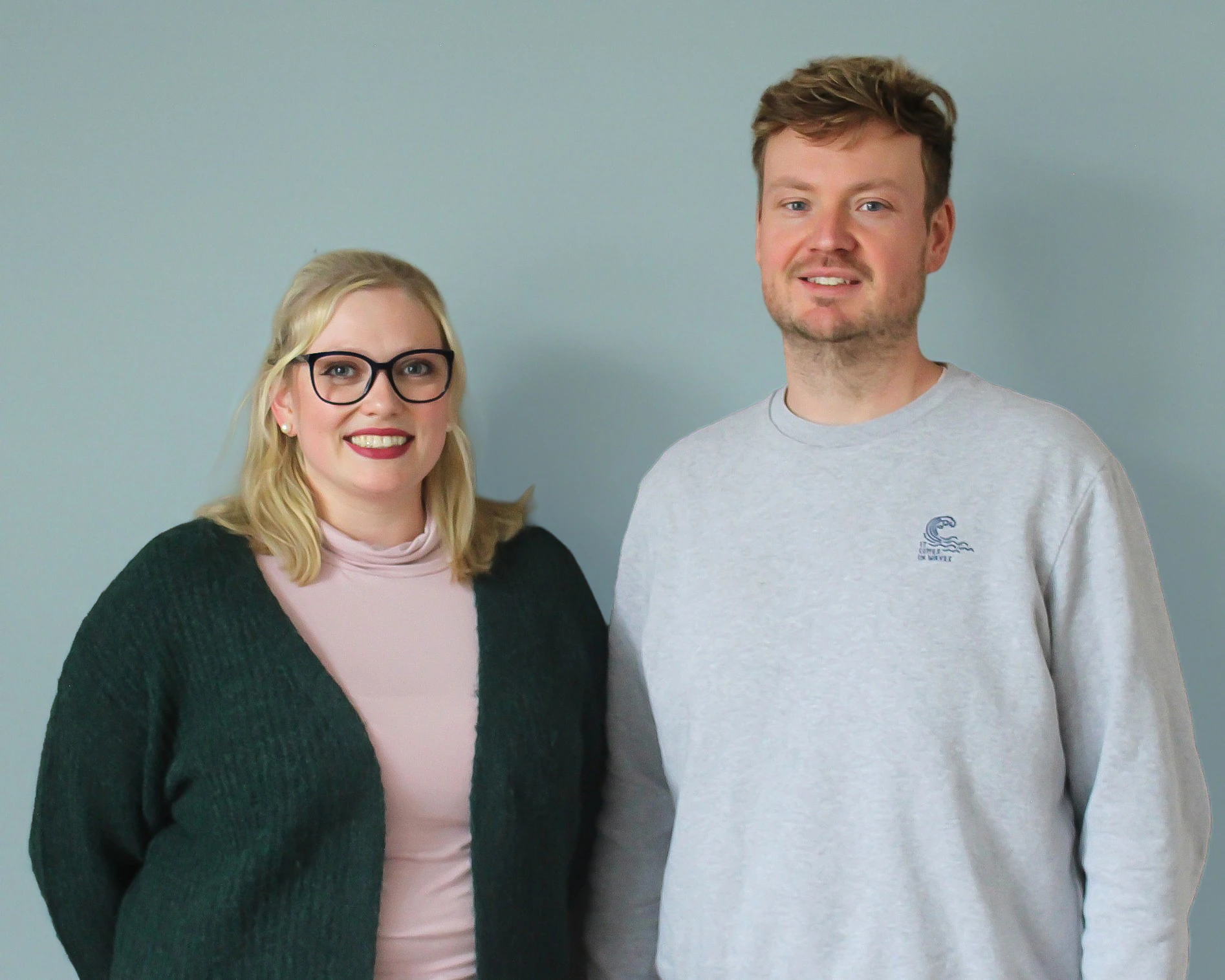 Fotografie von Jana Lena Jünger und Stefan Zeppenfeld, die Projektinitiator*innen von AKTIV vor blauen Grund.